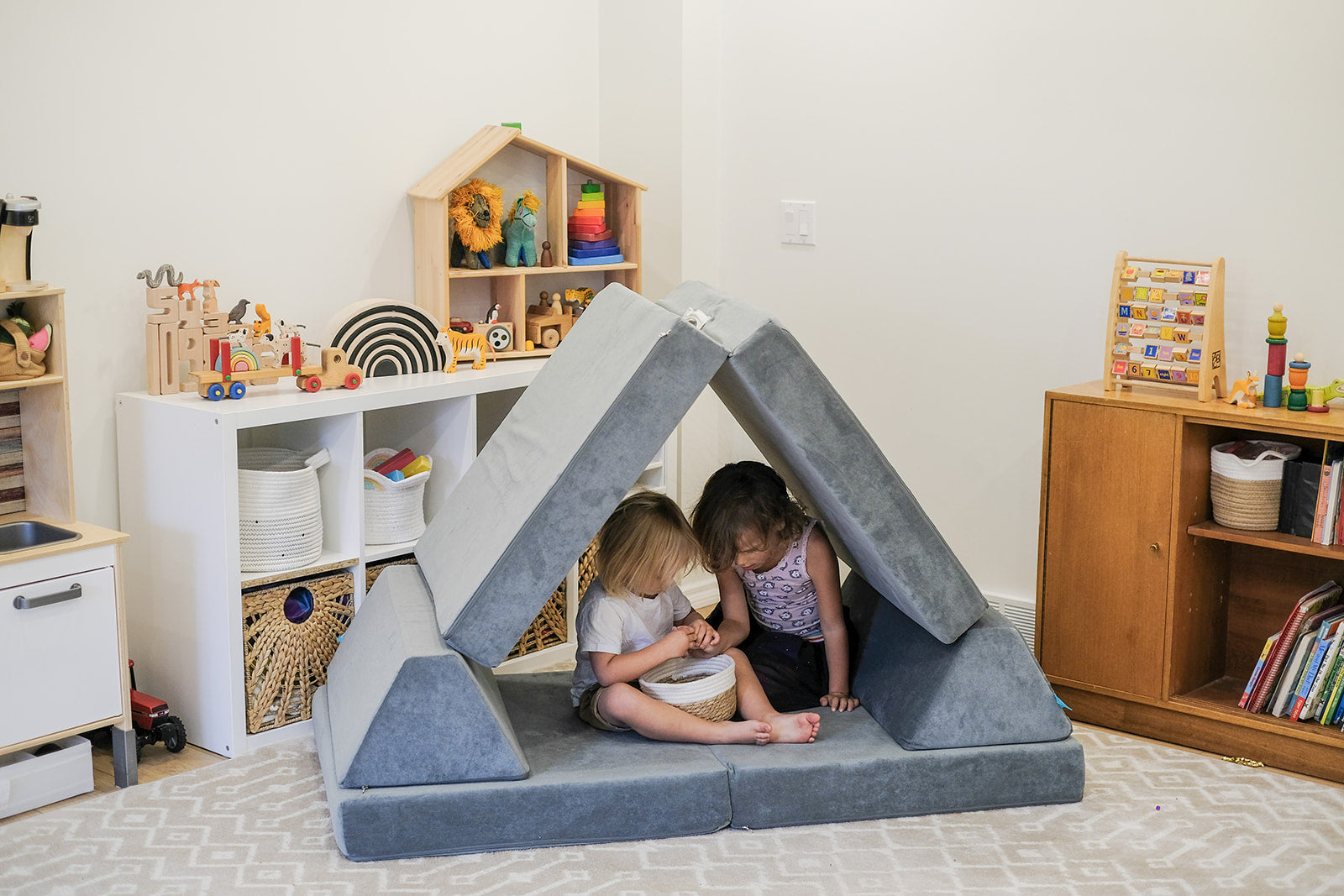 two kids playing with a grey play couch